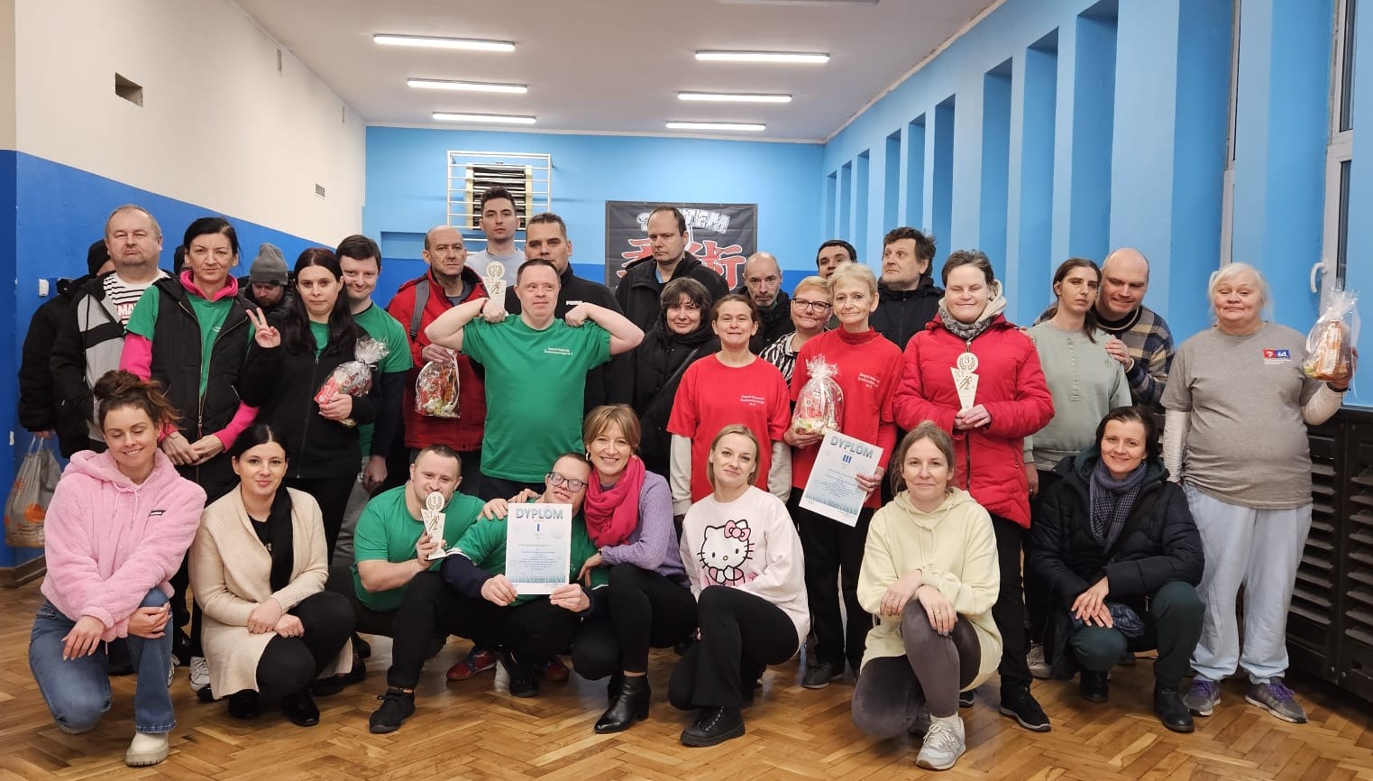 Grupa osób pozuje do zdjęcia z nagrodami i dyplomami.