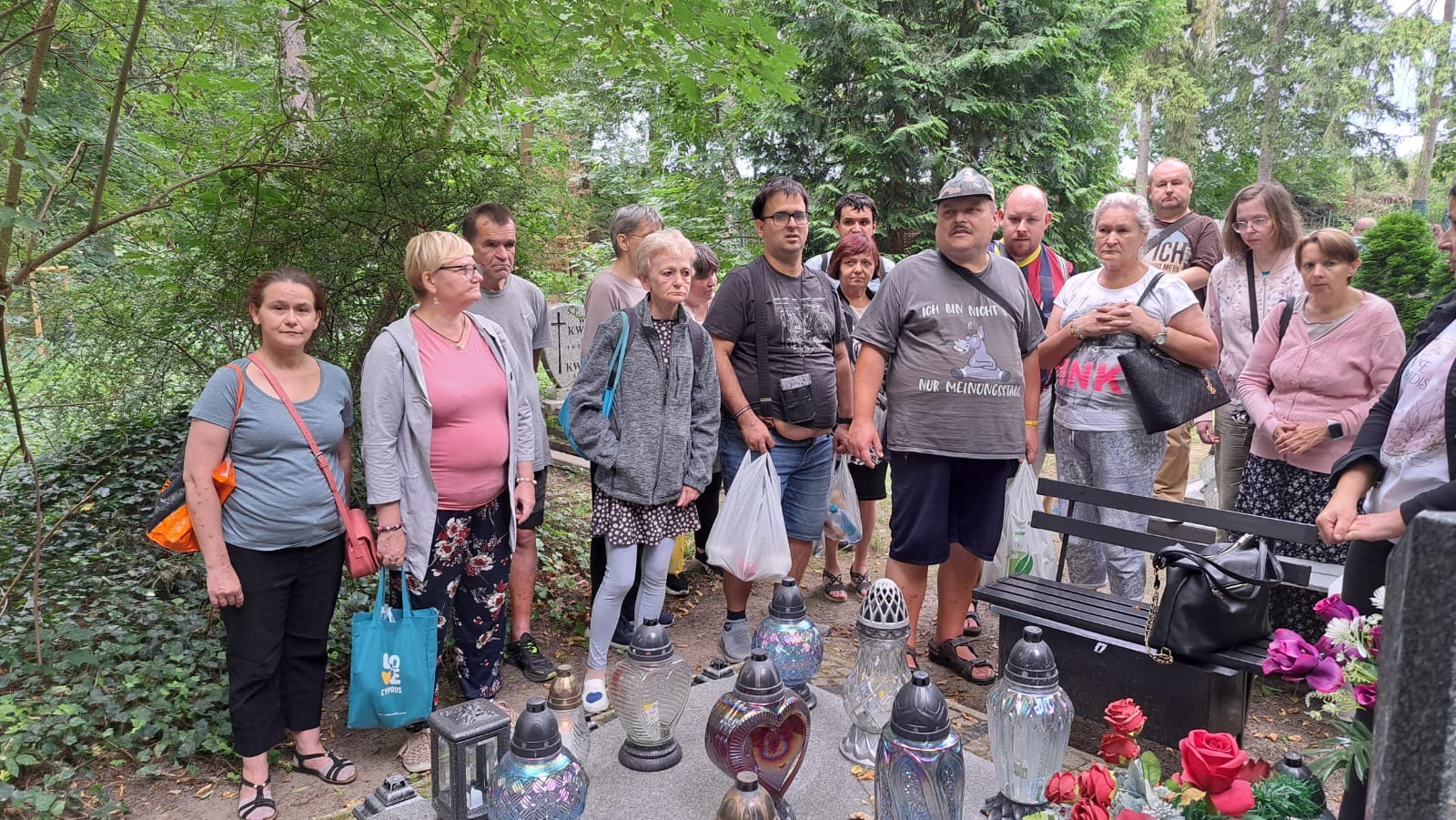 Grupa osób stoi przy grobie.