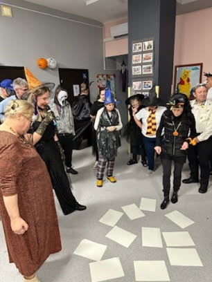 Grupa osób na sali tanecznej poprzebierana na zabawę helloweenową.