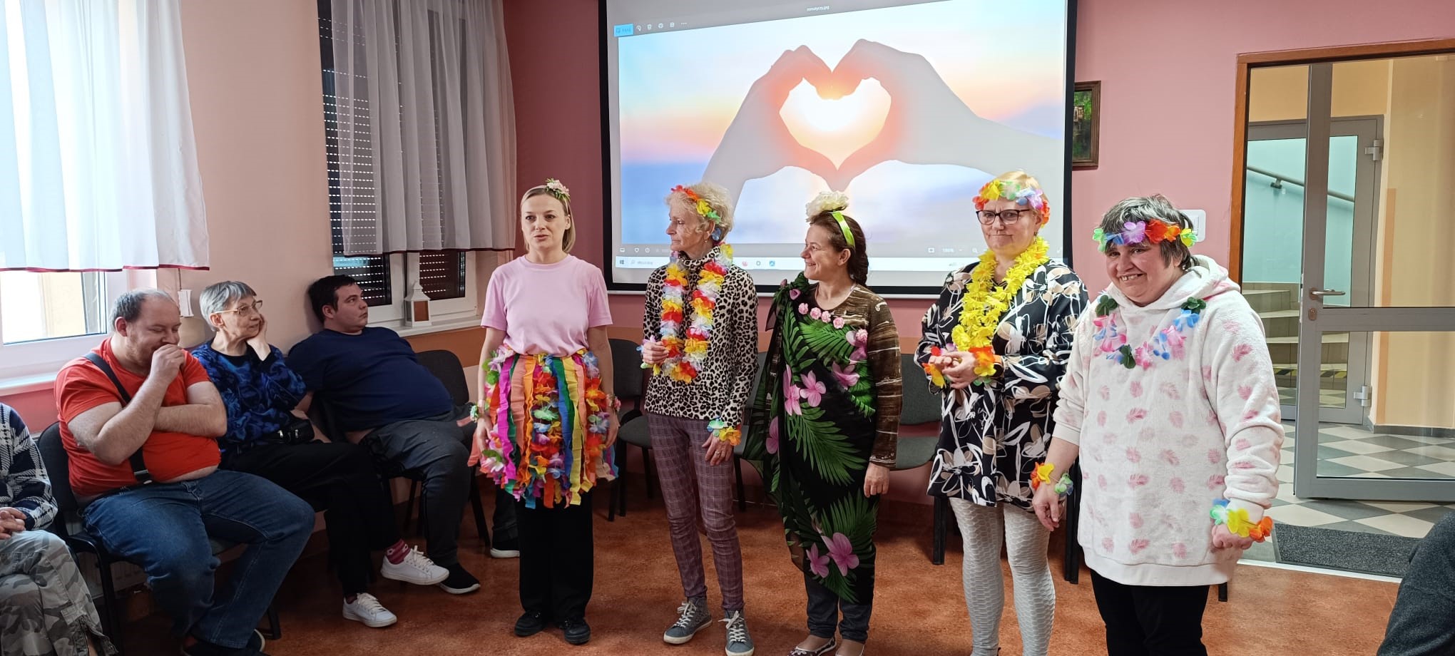 Grupa pań w przebraniach hawajskich stoi przed publicznością.