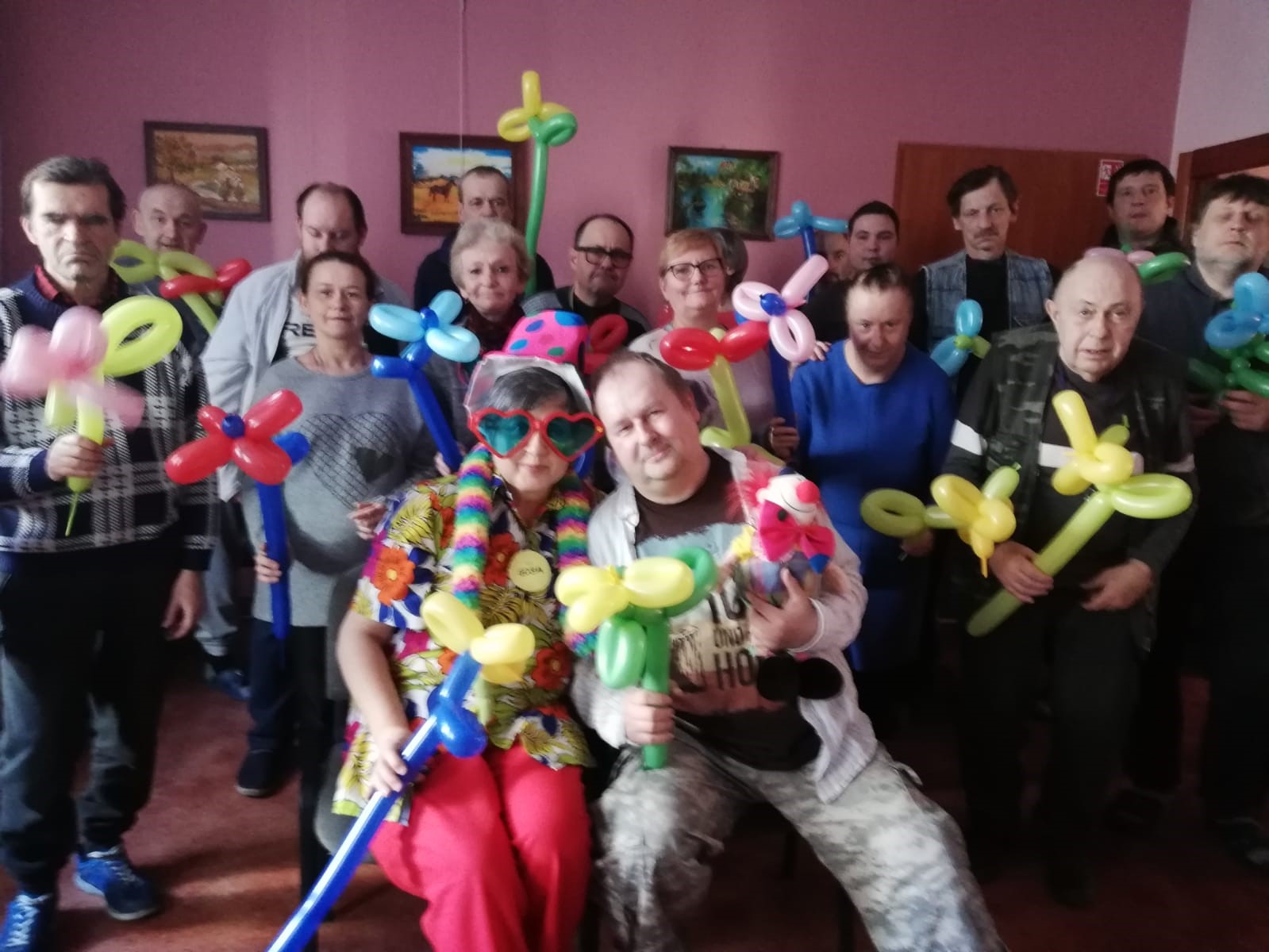 Grupa osób trzymająca kwiaty z balonów.