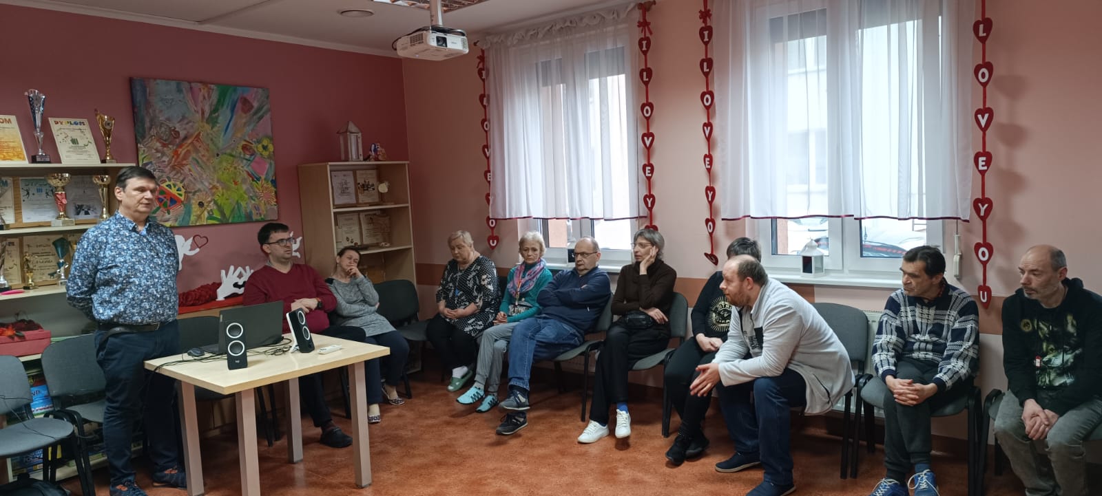 Wykładowca stoi przy siedzących słuchaczach.