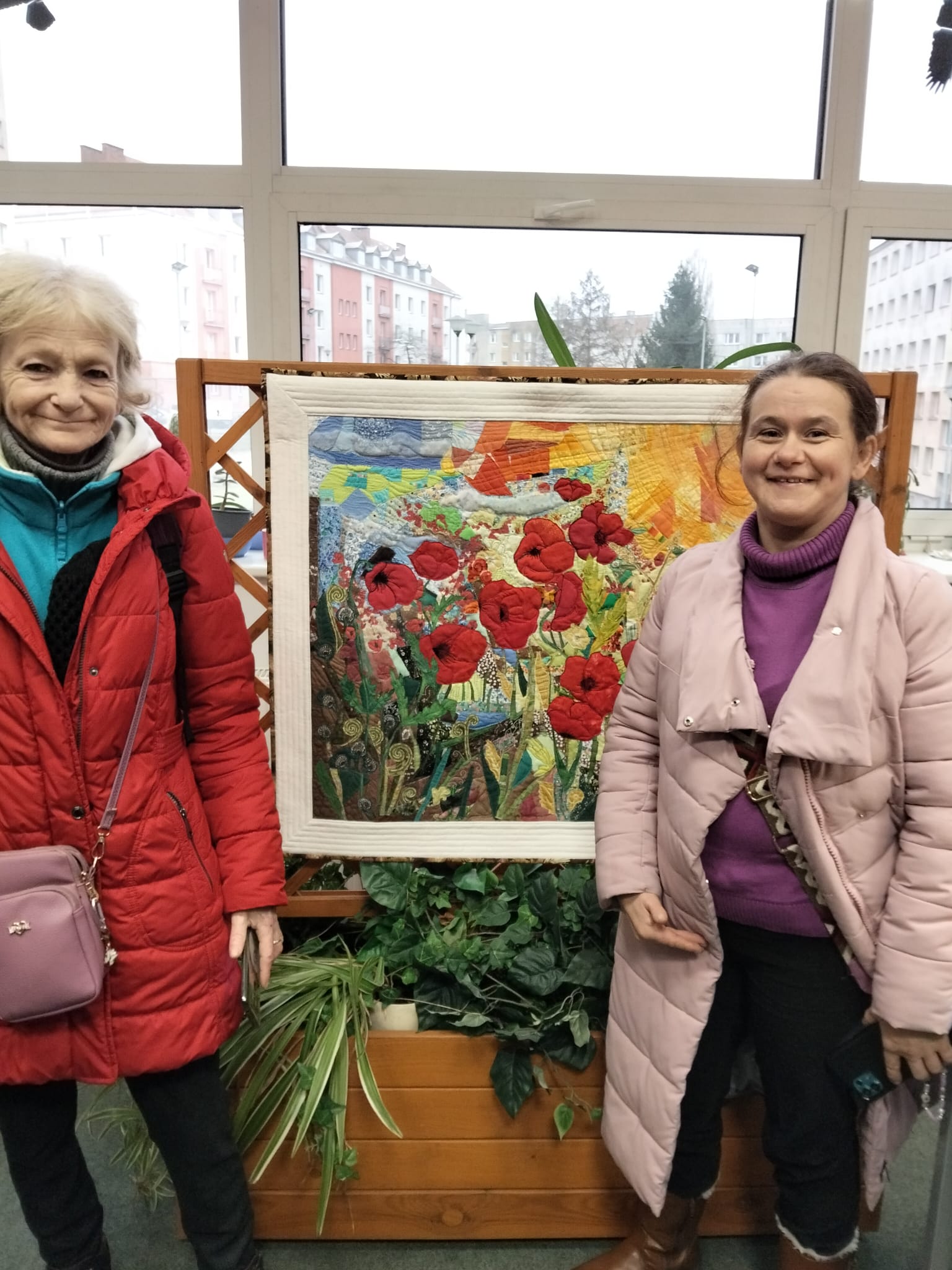 Dwie kobiety stoją pod kilimem na ścianie.