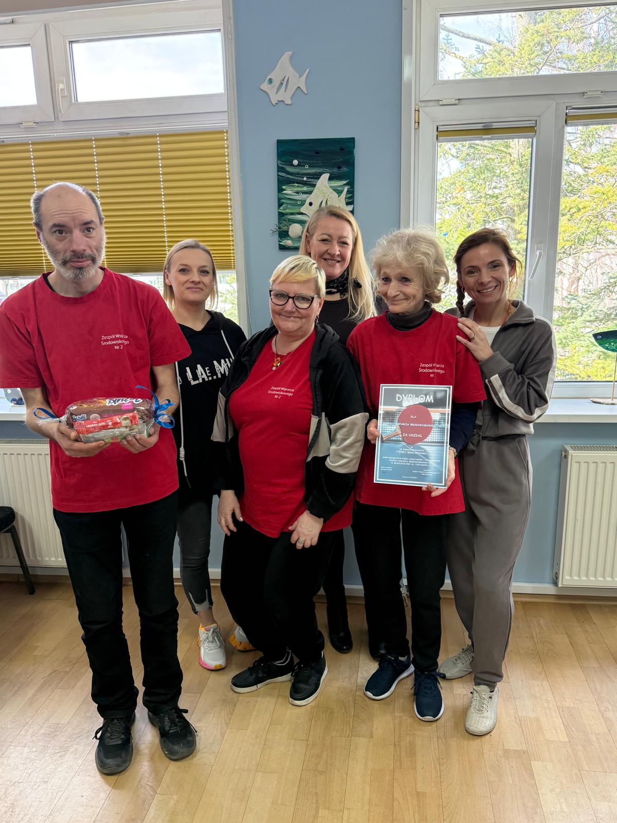 Grupa osób pozuje do zdjecia z dyplomami.