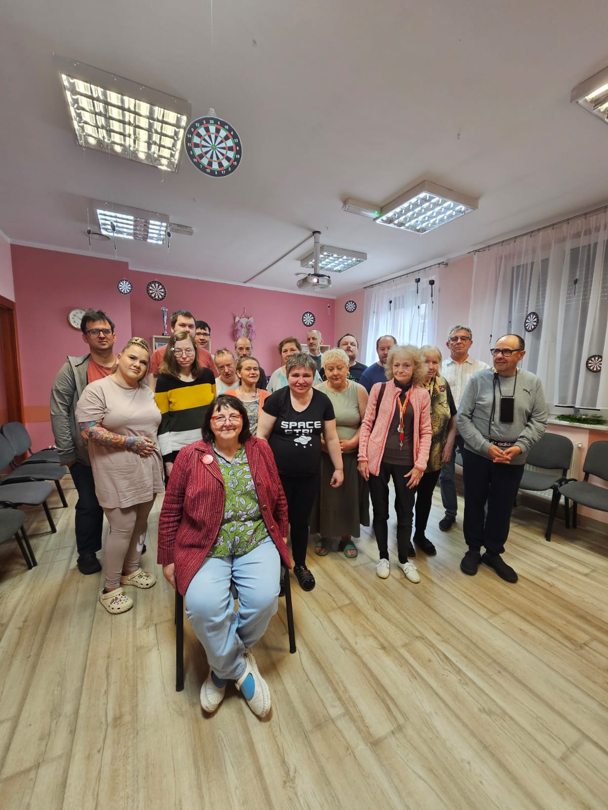 Grupa osób pozuje do zdjęcia osoba prowadząca wykład siedzi na krześle.
