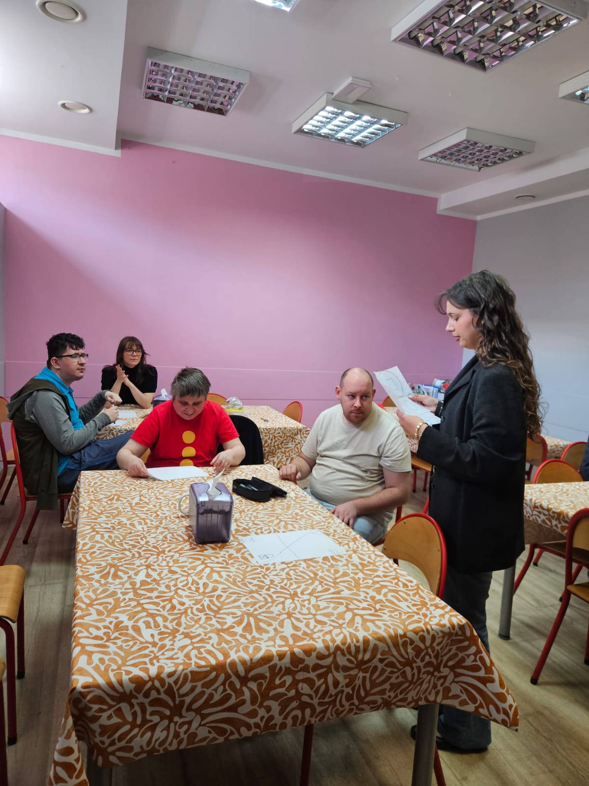 W pomieszczeniu kuchennym siedzą cztery osoby a piąta osoba czyta temat zajęć.
