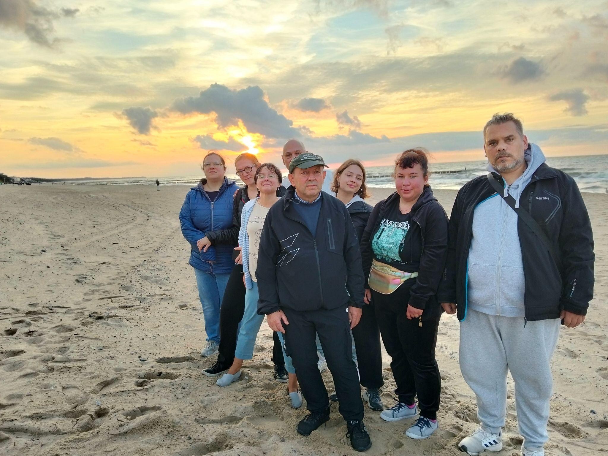 Grupa ośmiu osób pozująca do zdjęcia na tle morza.