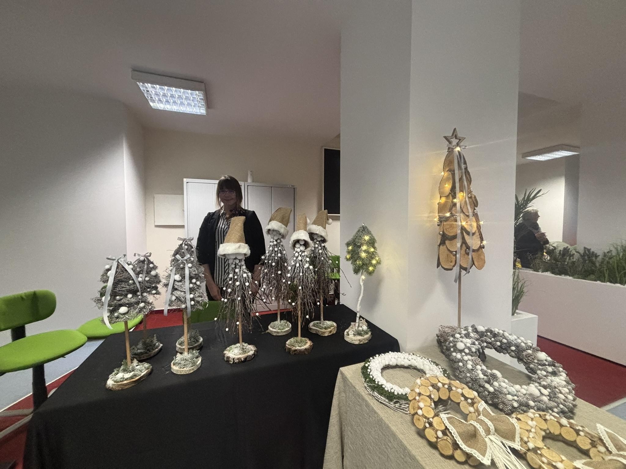 Jedna osoba stojąca w cieniu. Przed nią widać dwa stoliki na których stoją dekoracje świąteczne.