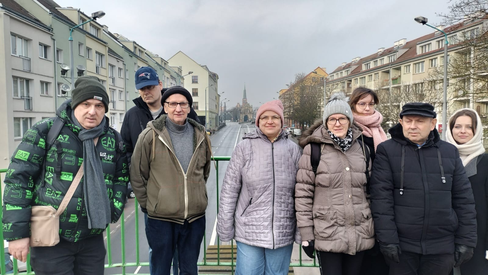 Osiem stojących osób. W tle widać bloki i drzewa.