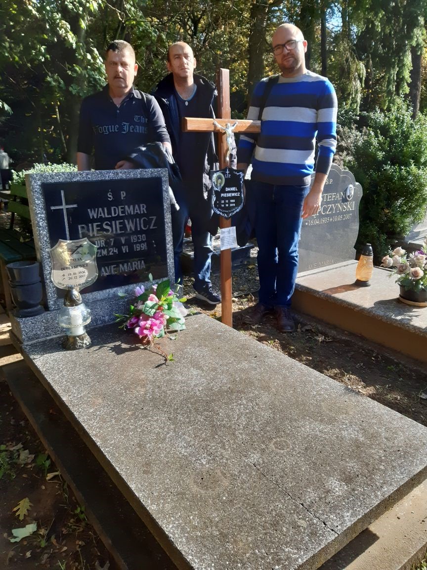 Troje mężczyzn przy grobie zmarłego Uczestnika.  