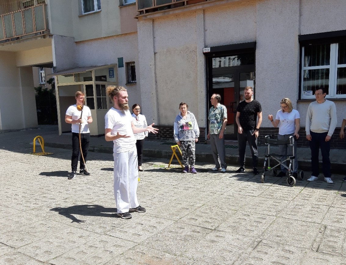 :Grupa ludzi podczas przebywająca na świeżym powietrzu podczas warsztatów „Capoeira”.