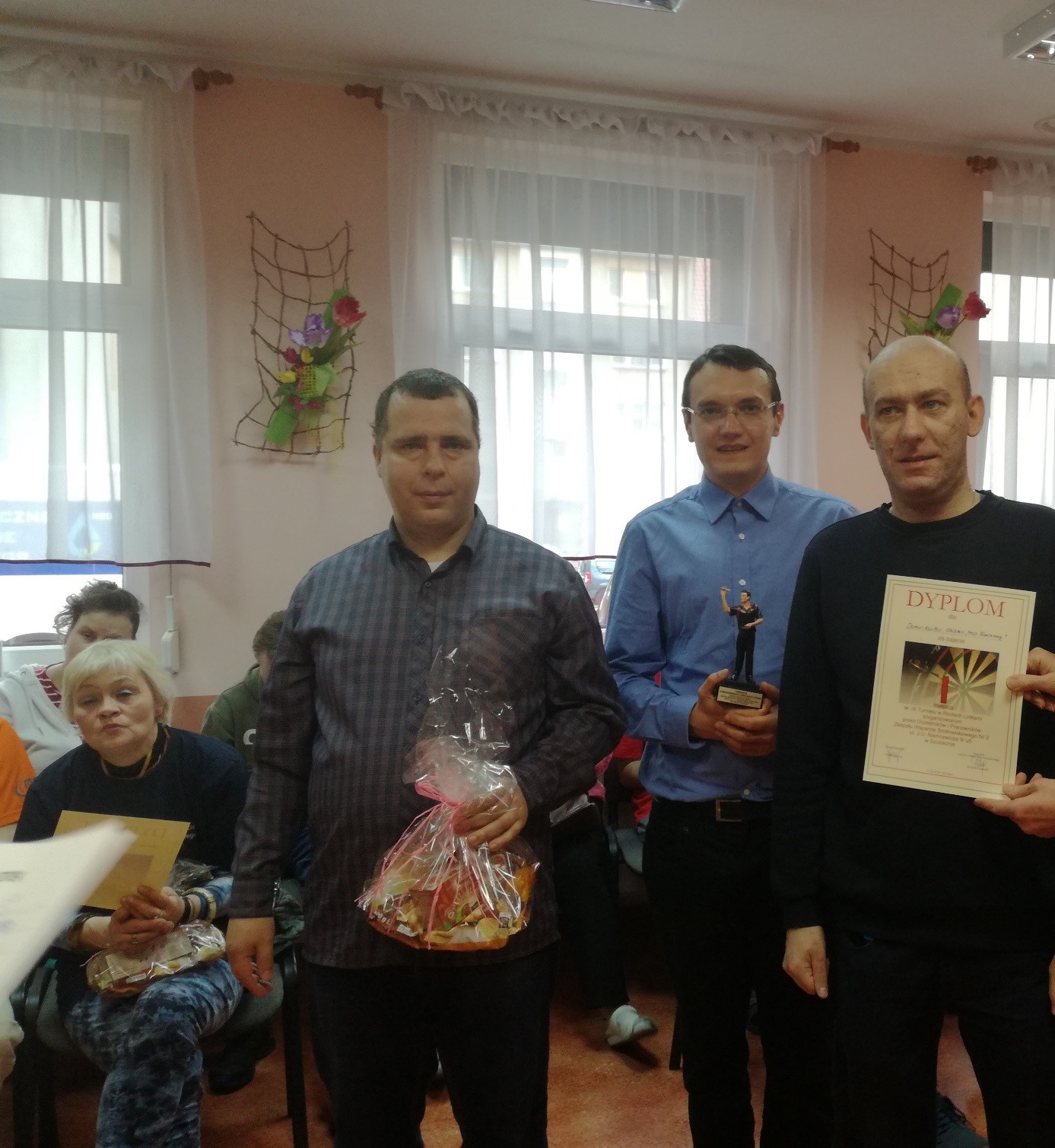Reprezentacja trzech mężczyzn Domu Klubu z dyplomem i nagrodami po turnieju rzutu lotkami. 