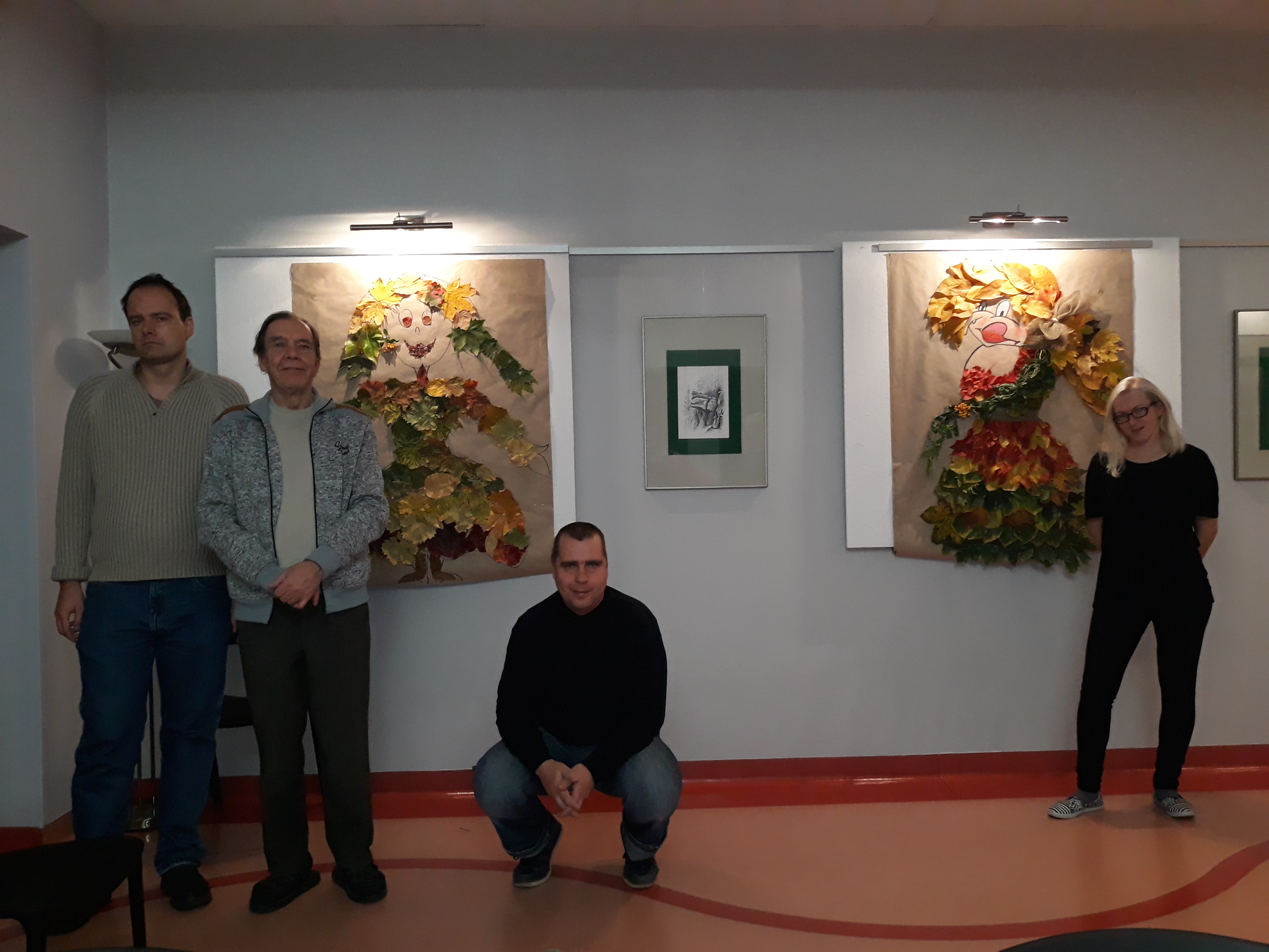 Grupa trzech osób przygotowująca pracę plastyczną z jesiennych liści. 