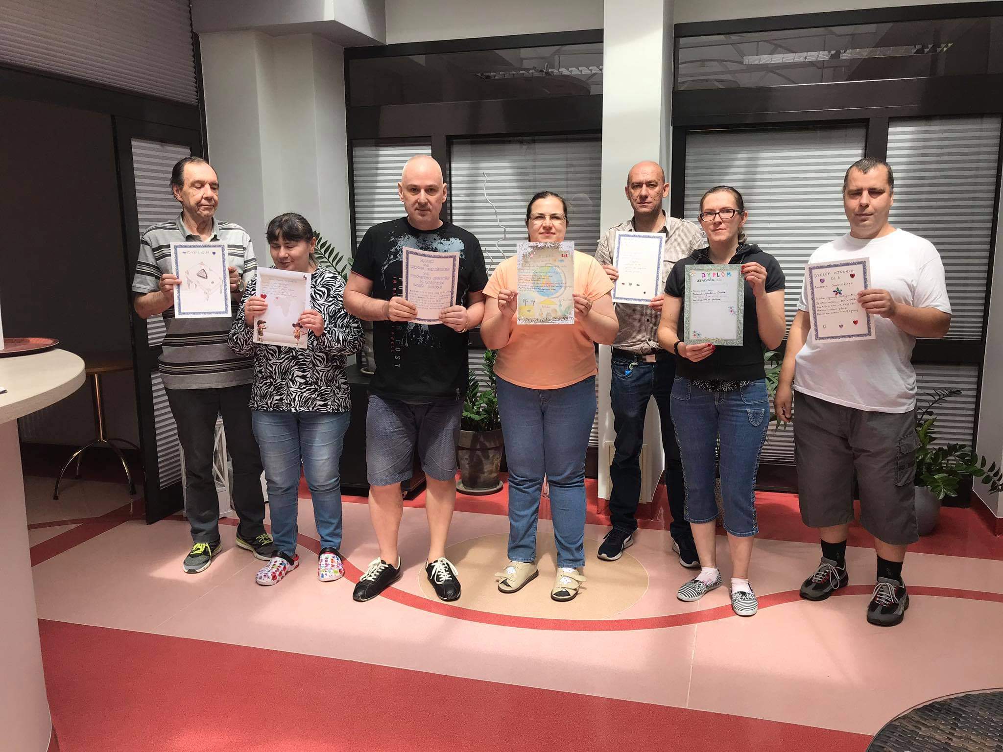 Grupa kobiet i mężczyzn prezentuje dyplomy.