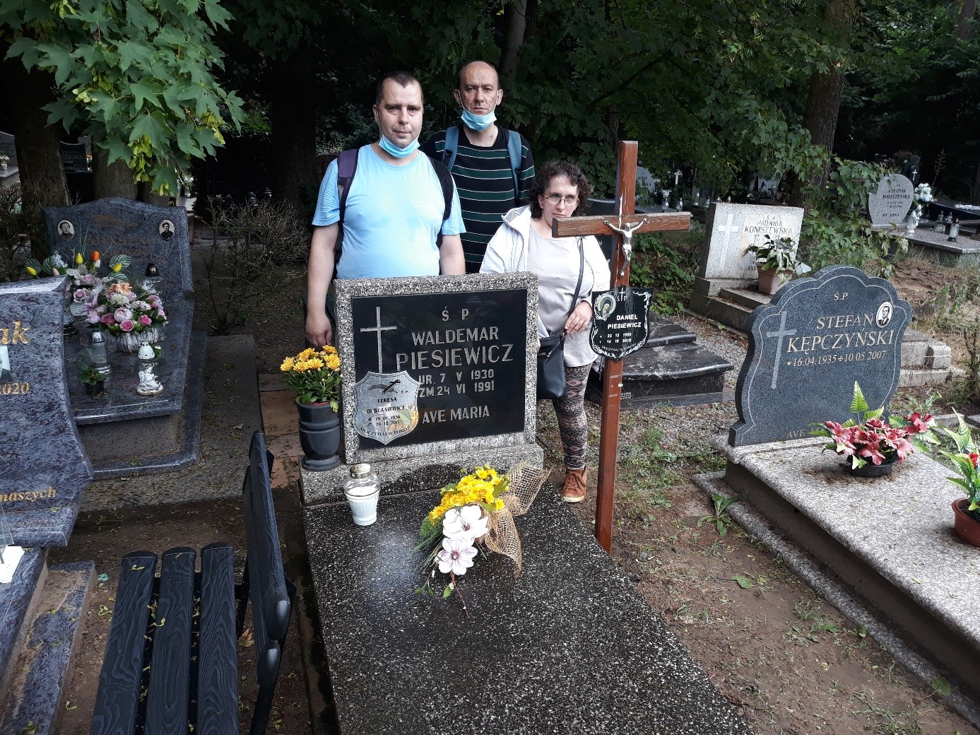 Dwóch mężczyzn i kobieta przy grobie kolegi. 
