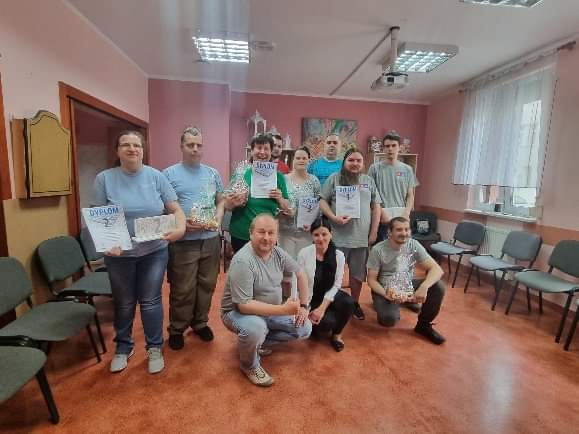 Grupa kobiet i mężczyzn z dyplomami i nagrodami. 