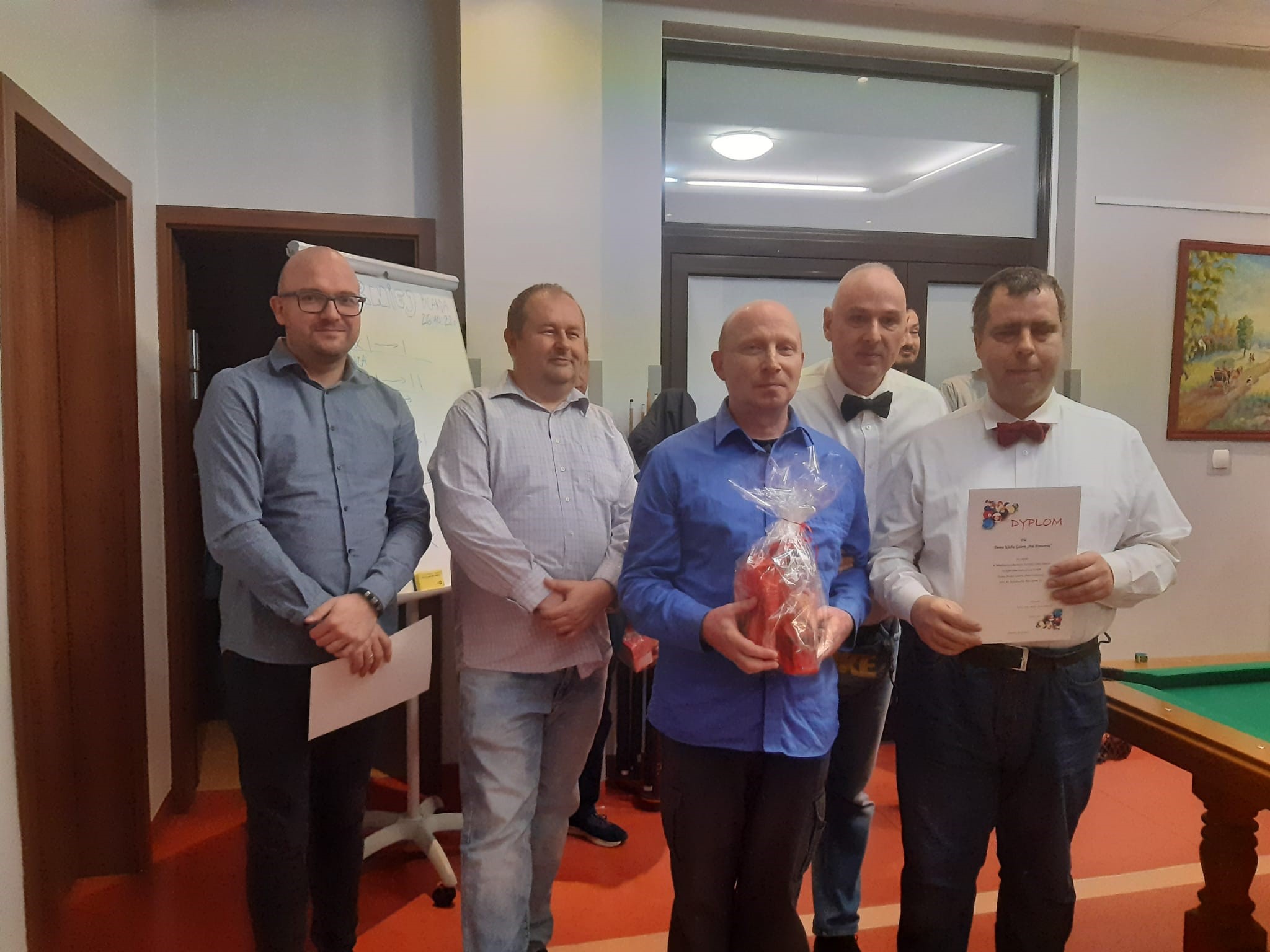 Grupa mężczyzn podczas dekoracji nagrodzonych w Turnieju Bilardowym. 