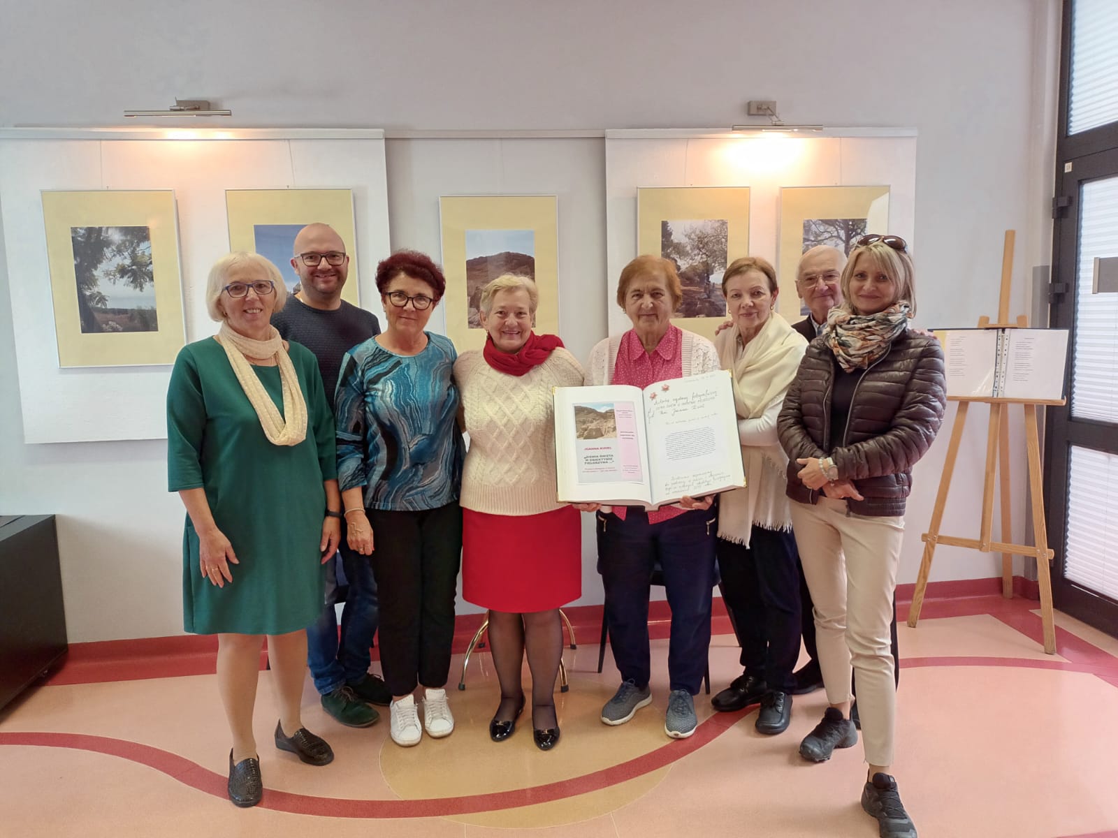 Grupa kobiet i mężczyzn pozująca na tle fotografii. 