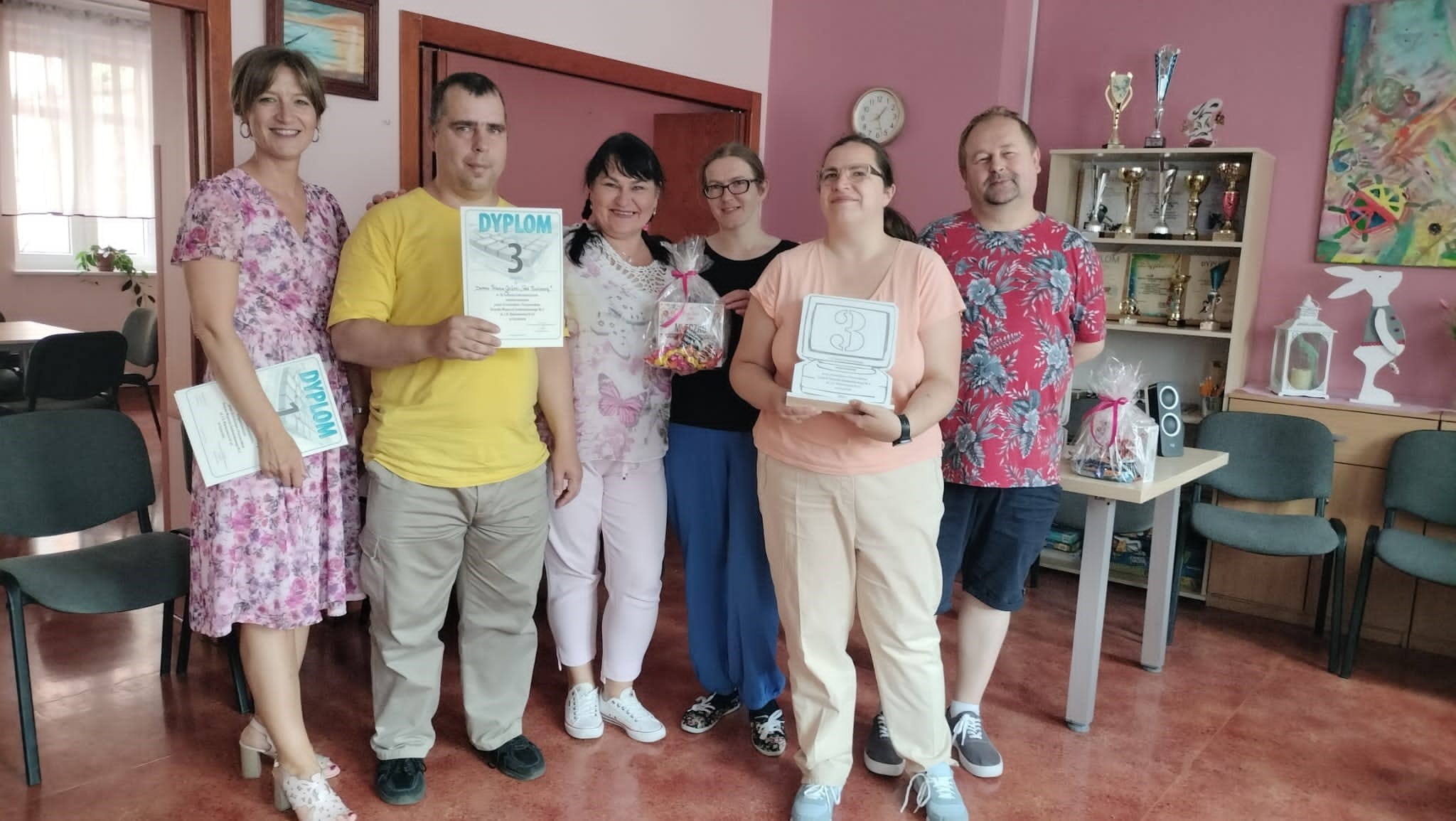 Grupa osób pozująca do zdjęcia wraz z dyplomami i upominkami. 