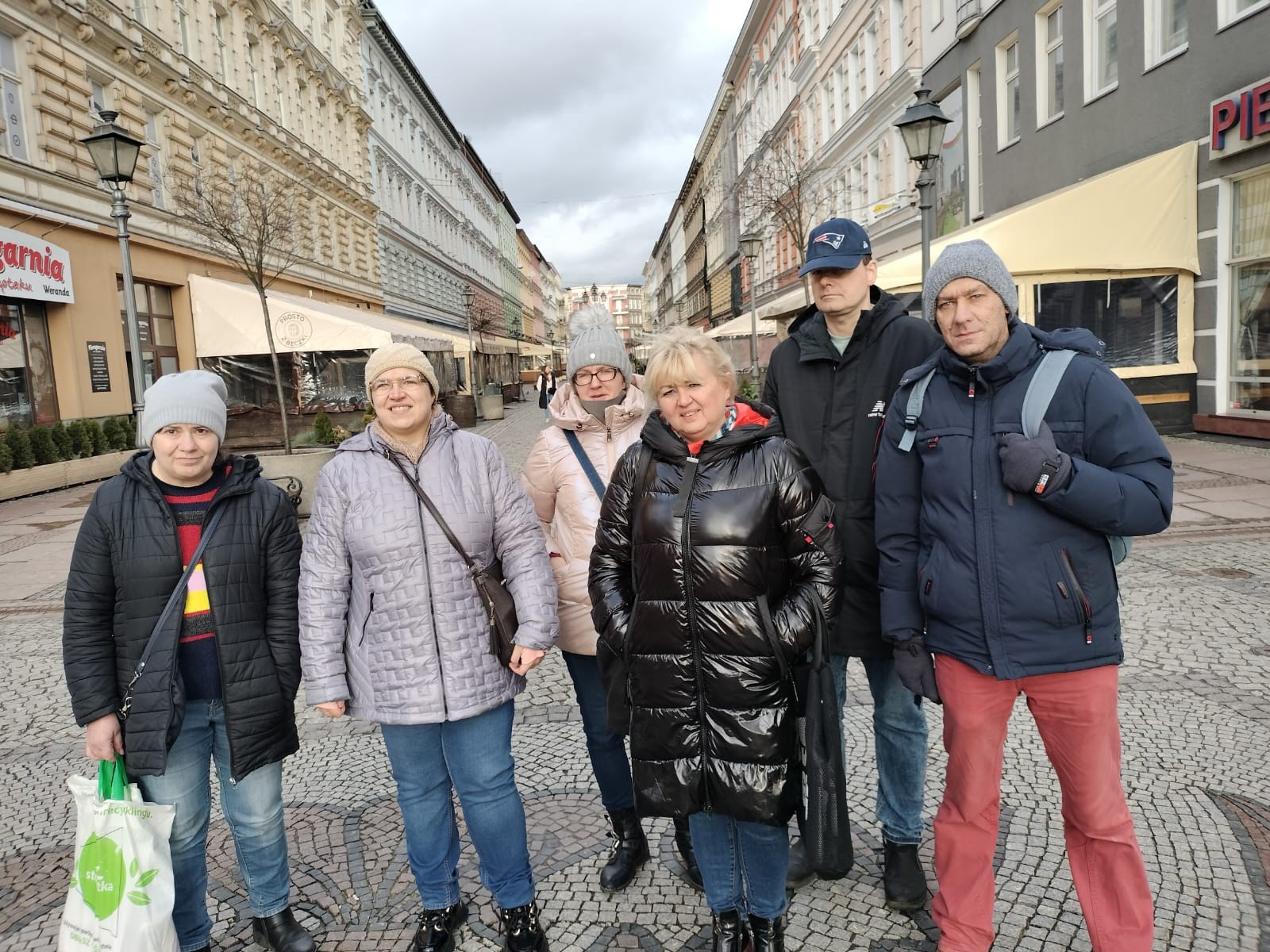 Grupa osób na tle zabytkowej architektury miasta. 