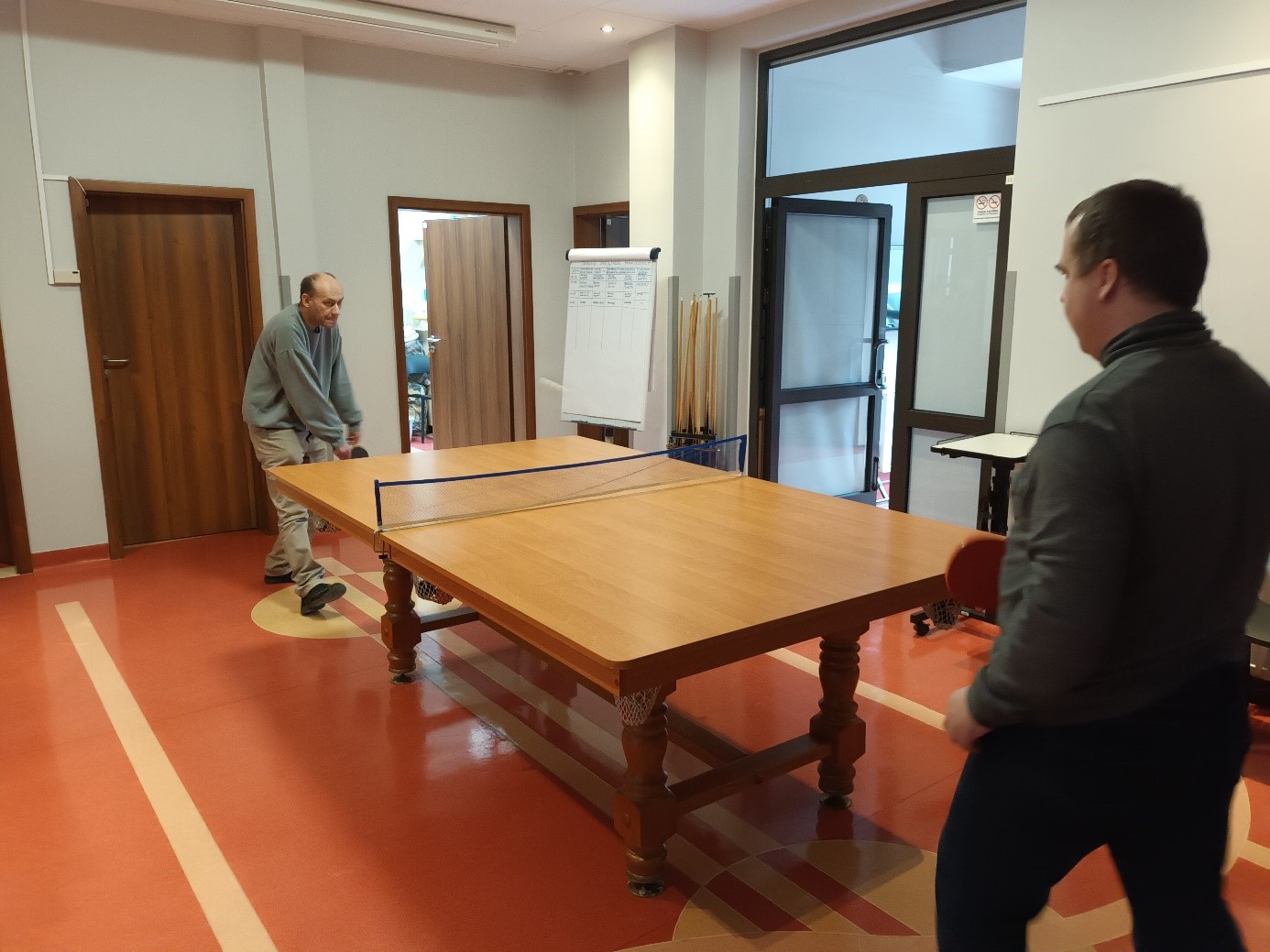 Dwóch mężczyzn grających  w tenisa stołowego. 