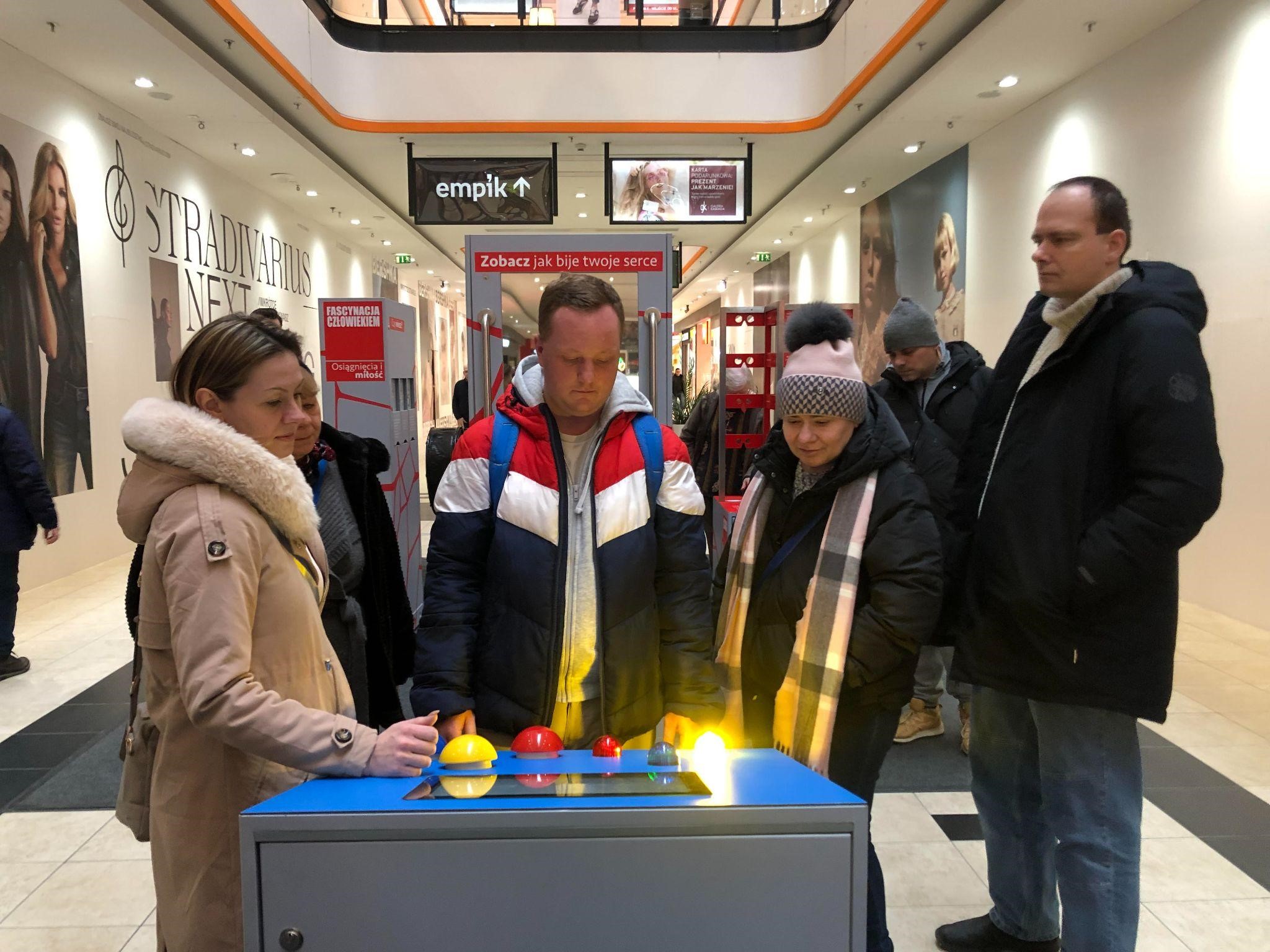 Grupa osób korzystająca z stacji interaktywnej.