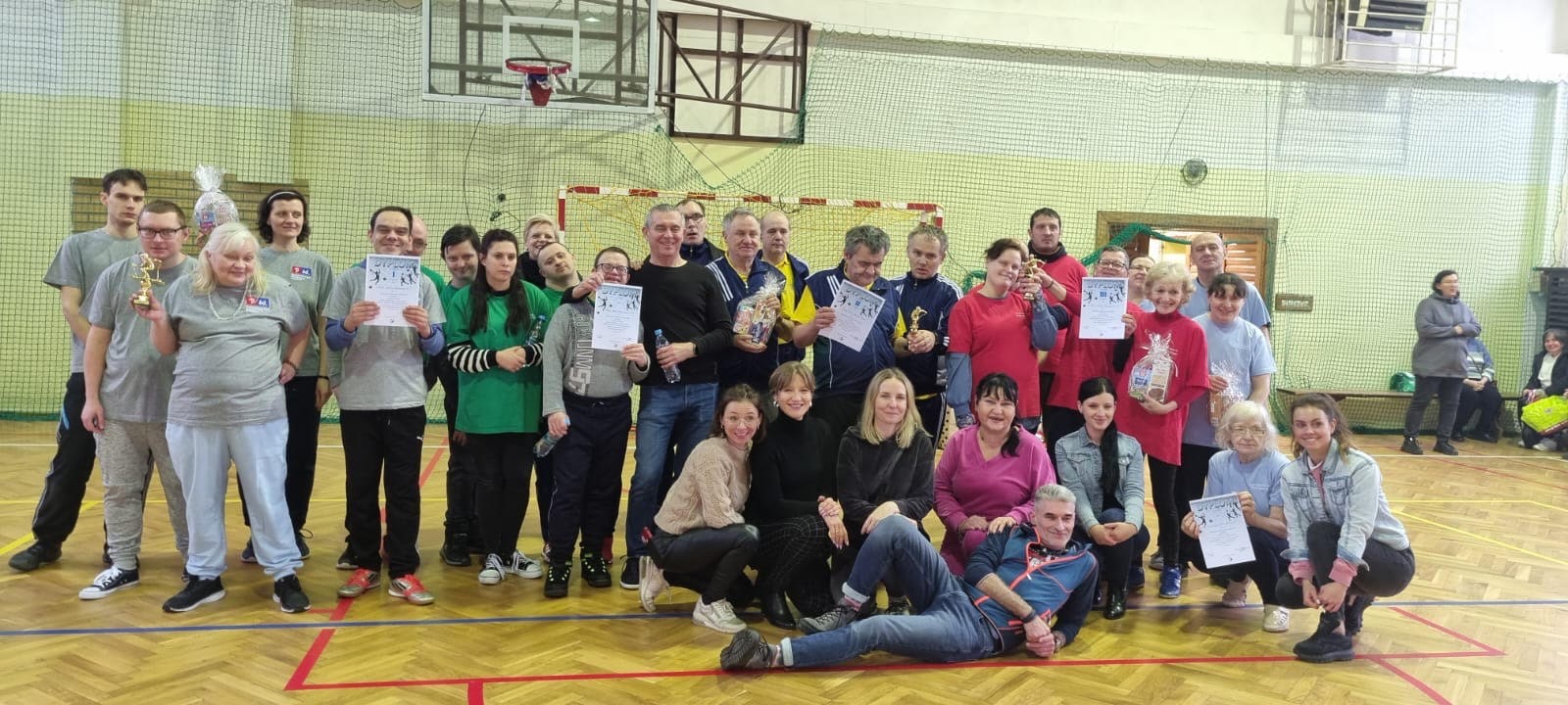 Grupa osób pozująca na sali gimnastycznej.