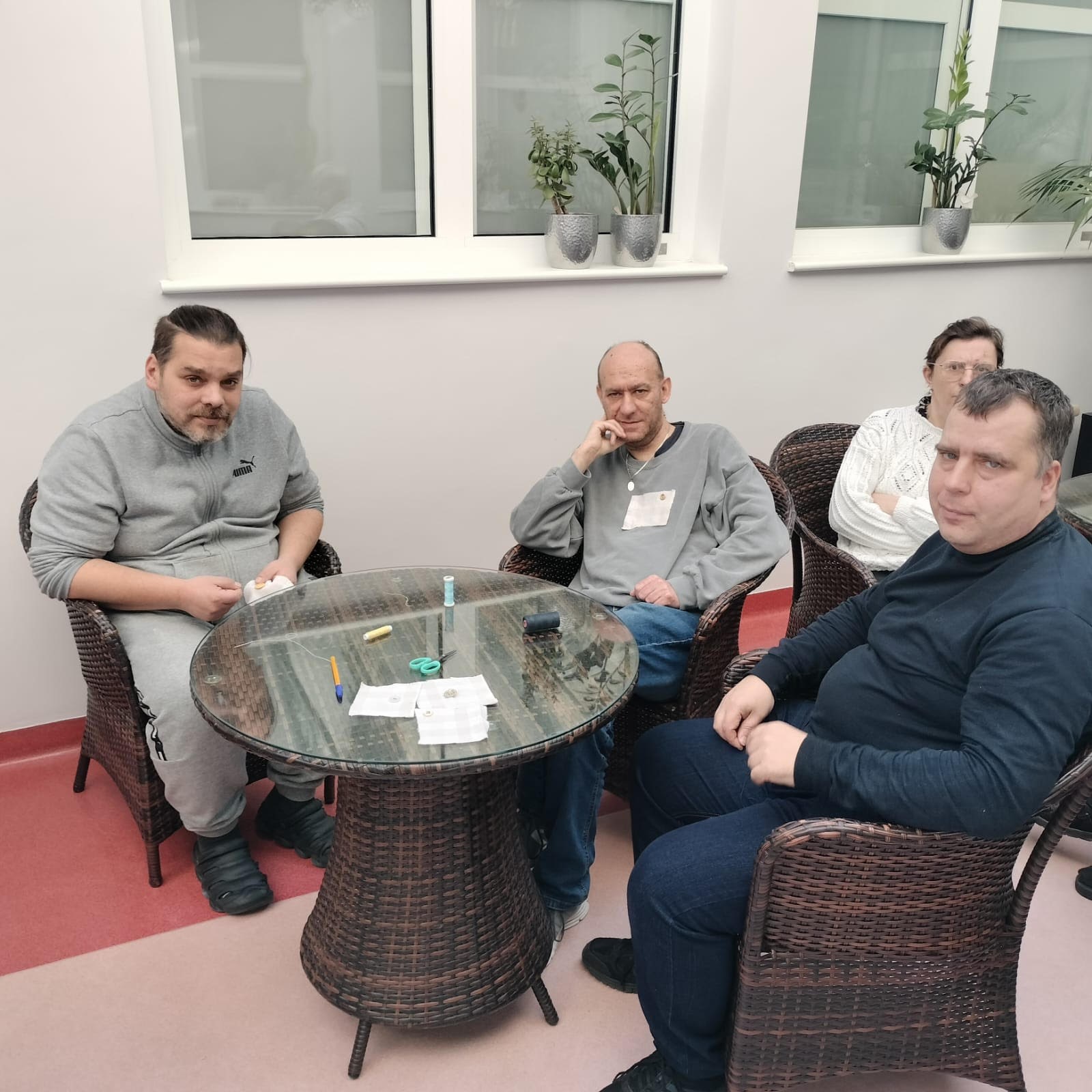 Trzech mężczyzn oraz jedna kobieta siedzący na fotelach z techno ratanu. 