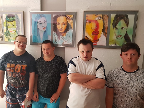 Czterech uczestników stoi przy ścianie. Na ścianie wiszą obrazy. 