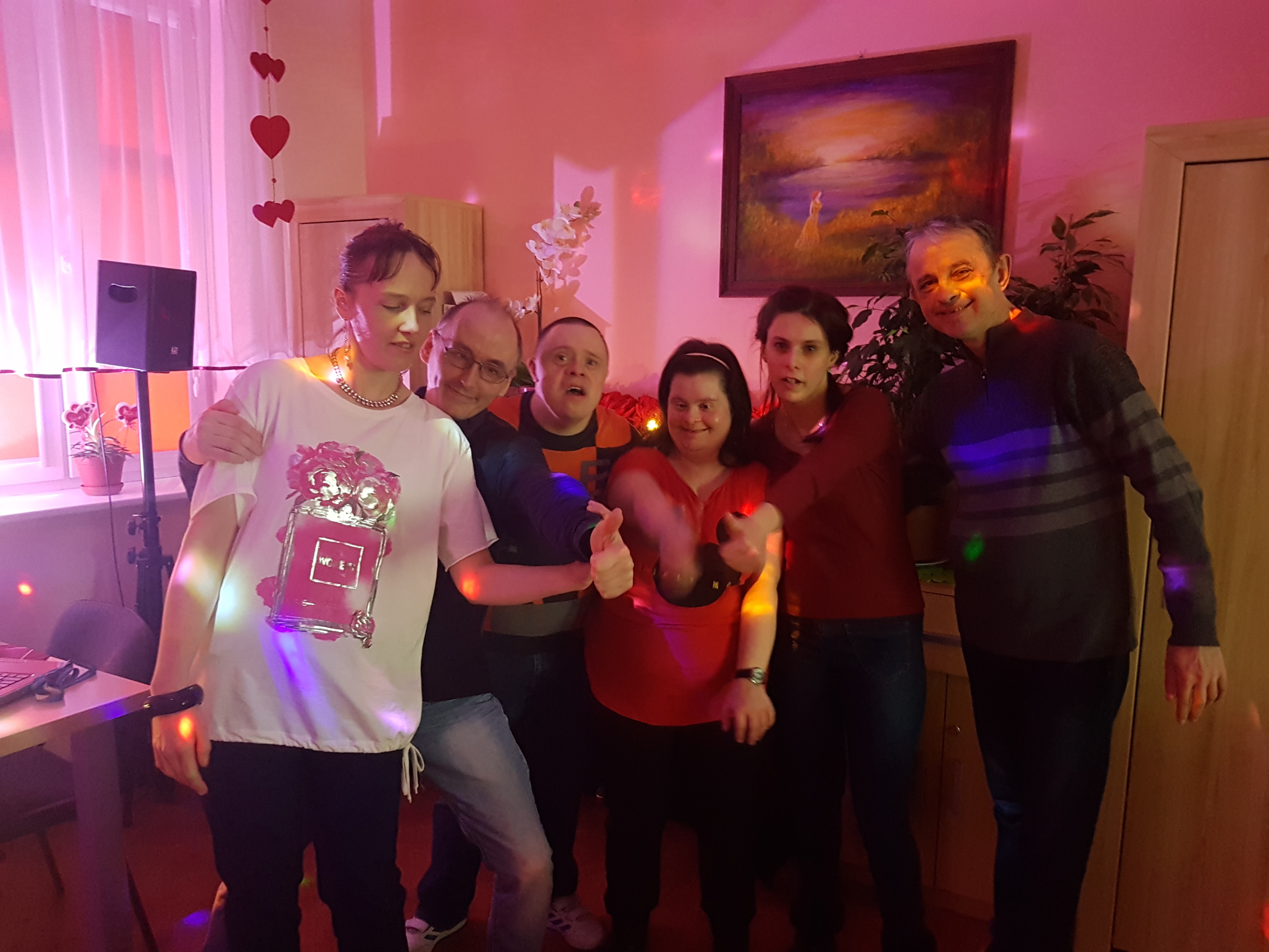 Grupa uczestników stoi obejmując się rękoma. Dwoje z nich pokazuje gest uniesionego kciuka do góry. 