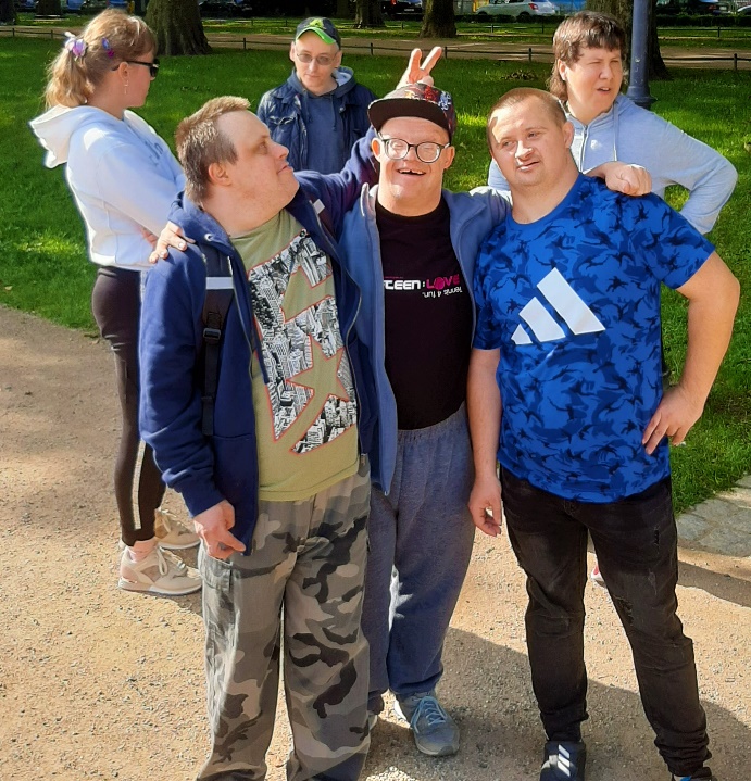 Grupa osób siedzących na ławce w parku.