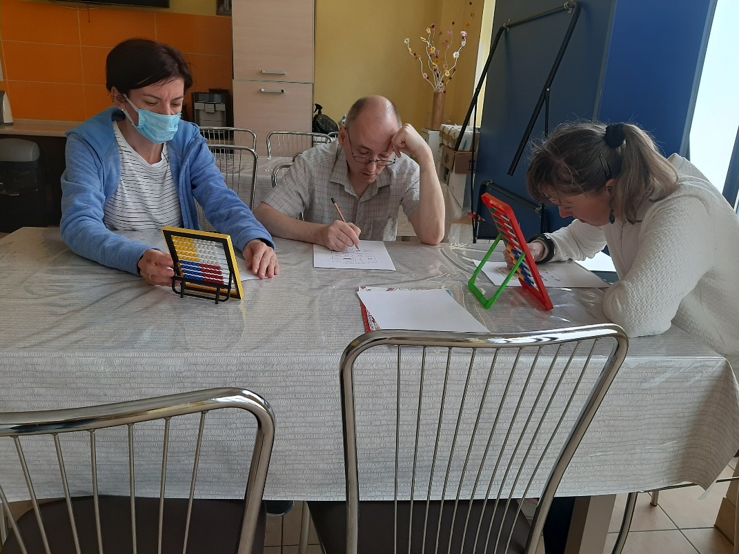 Trzy osoby rozwiązujące zadania matematyczne na liczydłach.