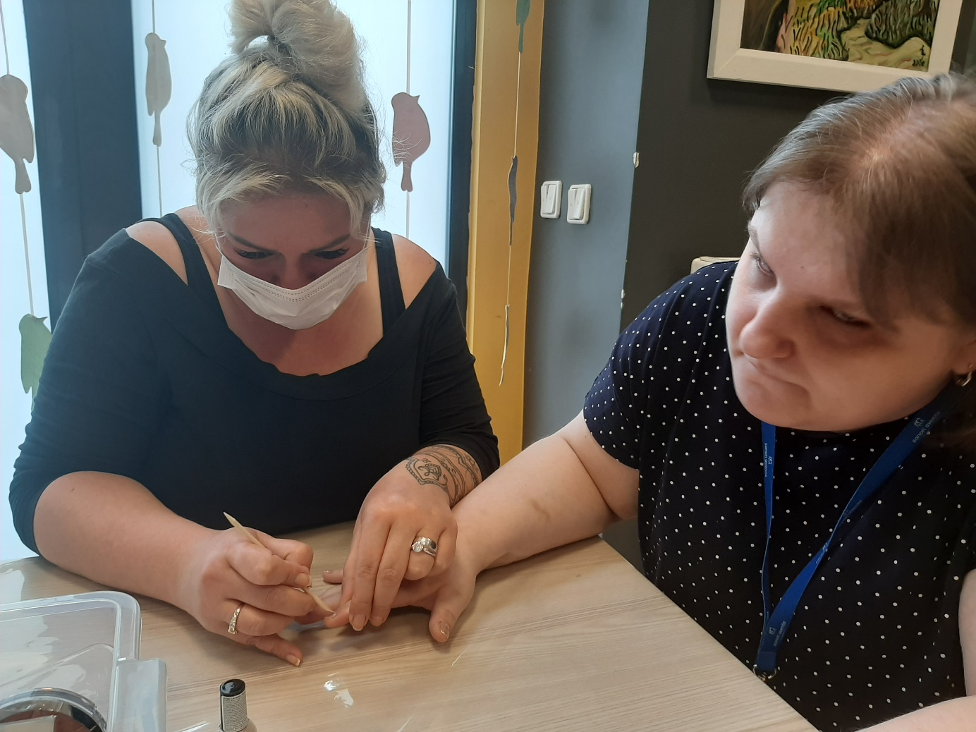 Terapeutka i uczestniczka podczas zabiegu manicure. 