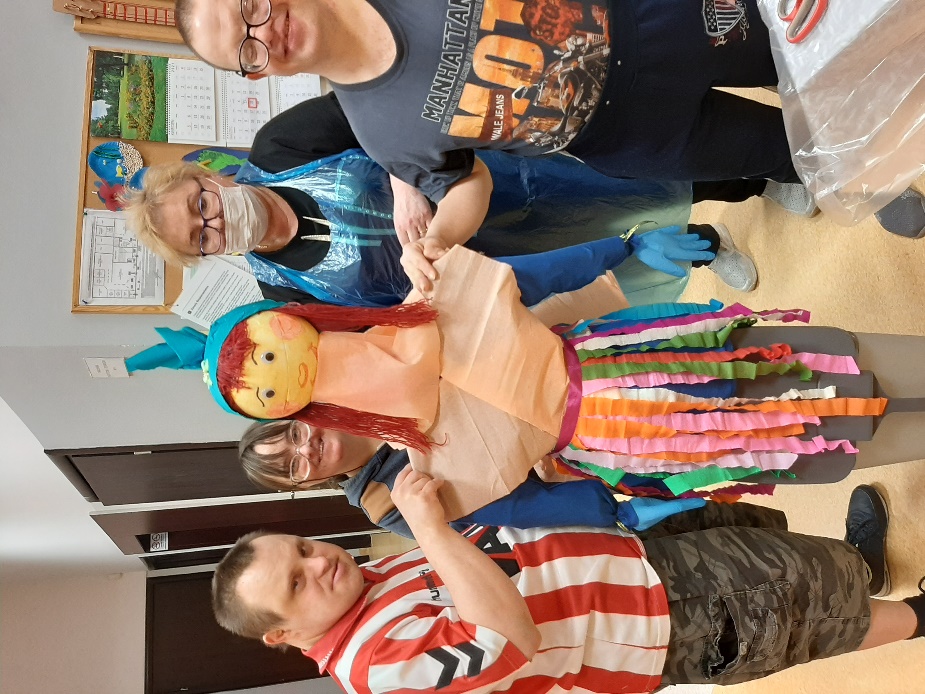 Dwóch mężczyzn i dwie kobiety trzymają wykonaną z papieru i bibuły kukłę marzanny.