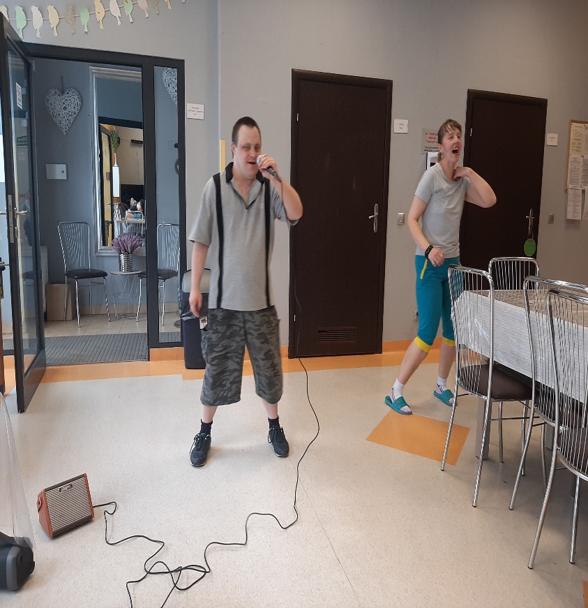 Mężczyzna trzymający mikrofon i kobieta tańcząca obok niego.