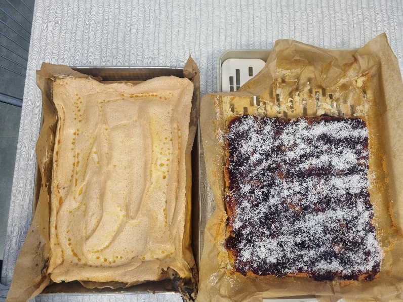 Na stole leżą dwie blachy ciast. 