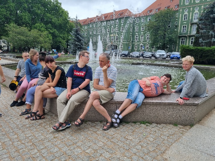 Kobiety i mężczyźni siedzą przy fontannie.