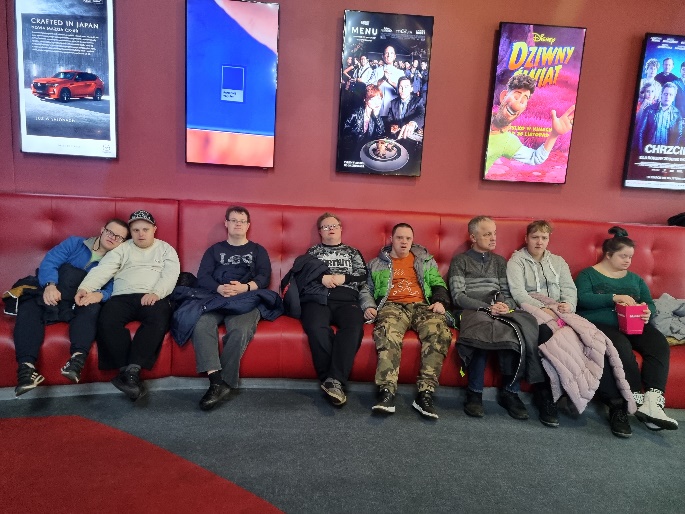 Kobiety i mężczyźni siedzą na sofie. 