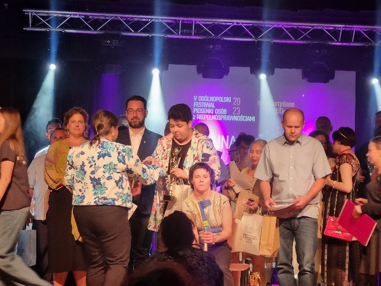 Kobiety i mężczyźni stoją na scenie i odbierają nagrody.