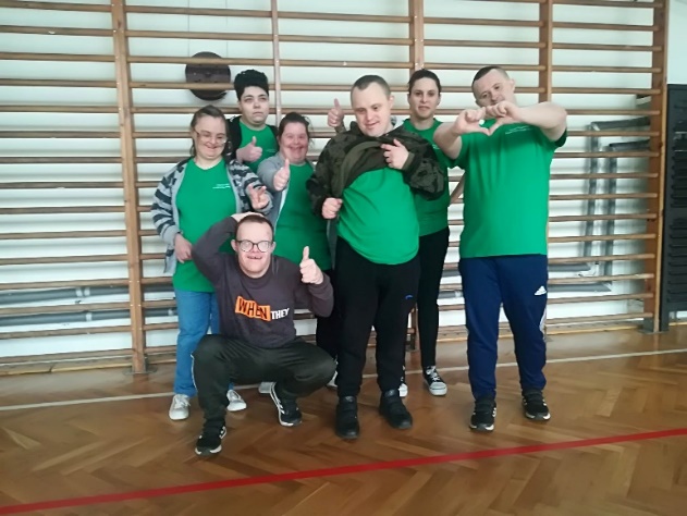Kobiety i mężczyźni stoją i patrzą w obiektyw aparatu fotograficznego.