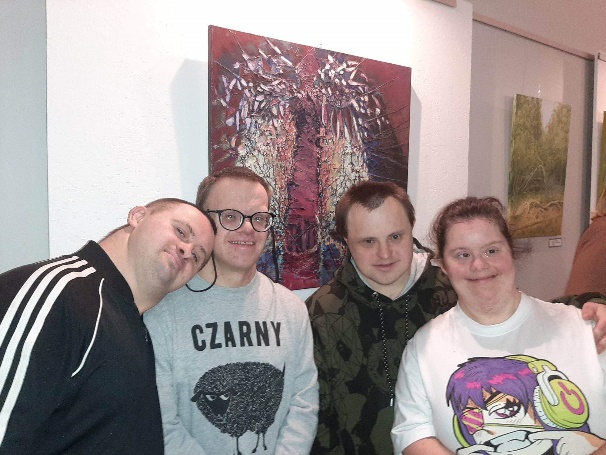 Kobieta i trzech mężczyzn stoją przy obrazie.