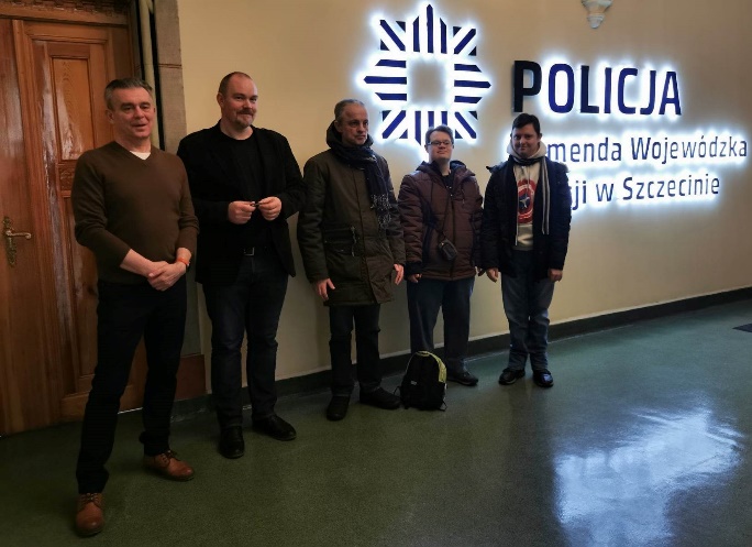 Mężczyźni stoją i patrzą w obiektyw aparatu fotograficznego.