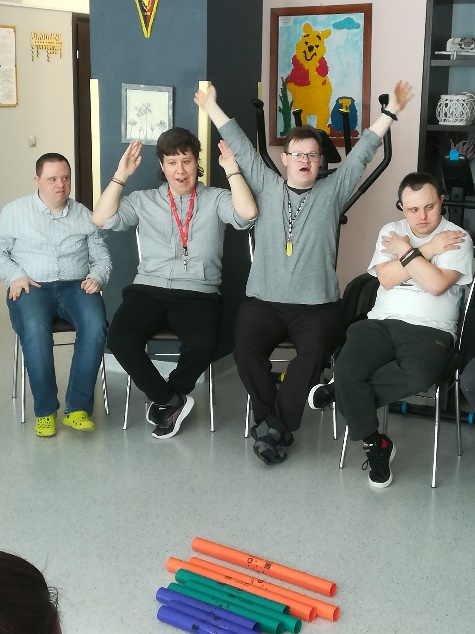 Kobiety i mężczyźni śpiewają i grają na instrumentach muzycznych.