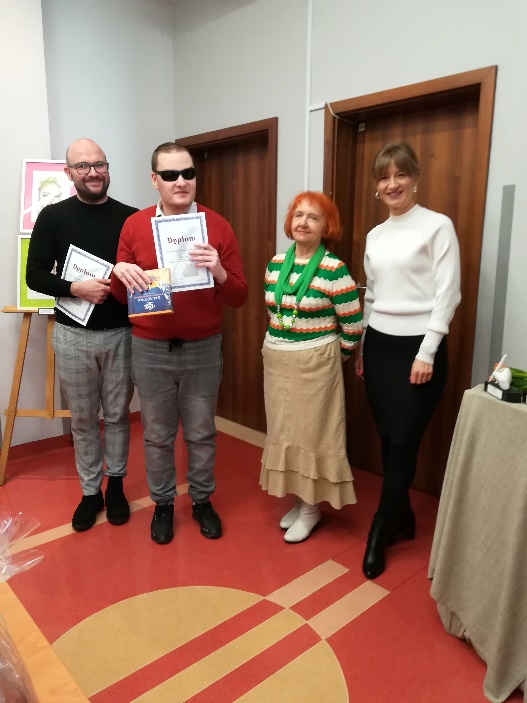 Kobiety i mężczyzna stoją i patrzą w obiektyw aparatu fotograficznego
