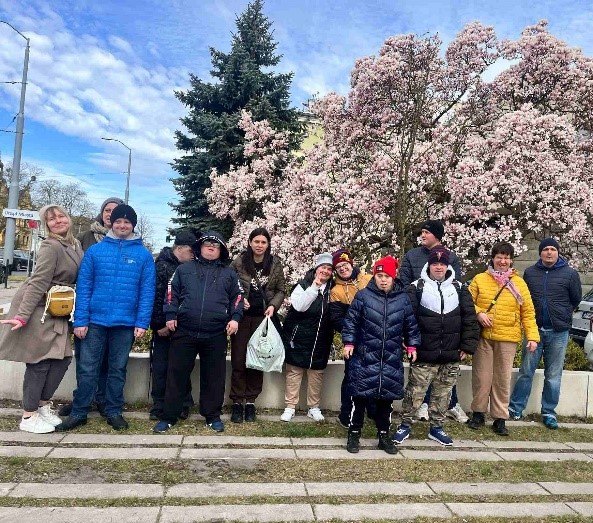 Grupa kobiet i mężczyzn na tle drzewa - kwitnącej magnolii. 