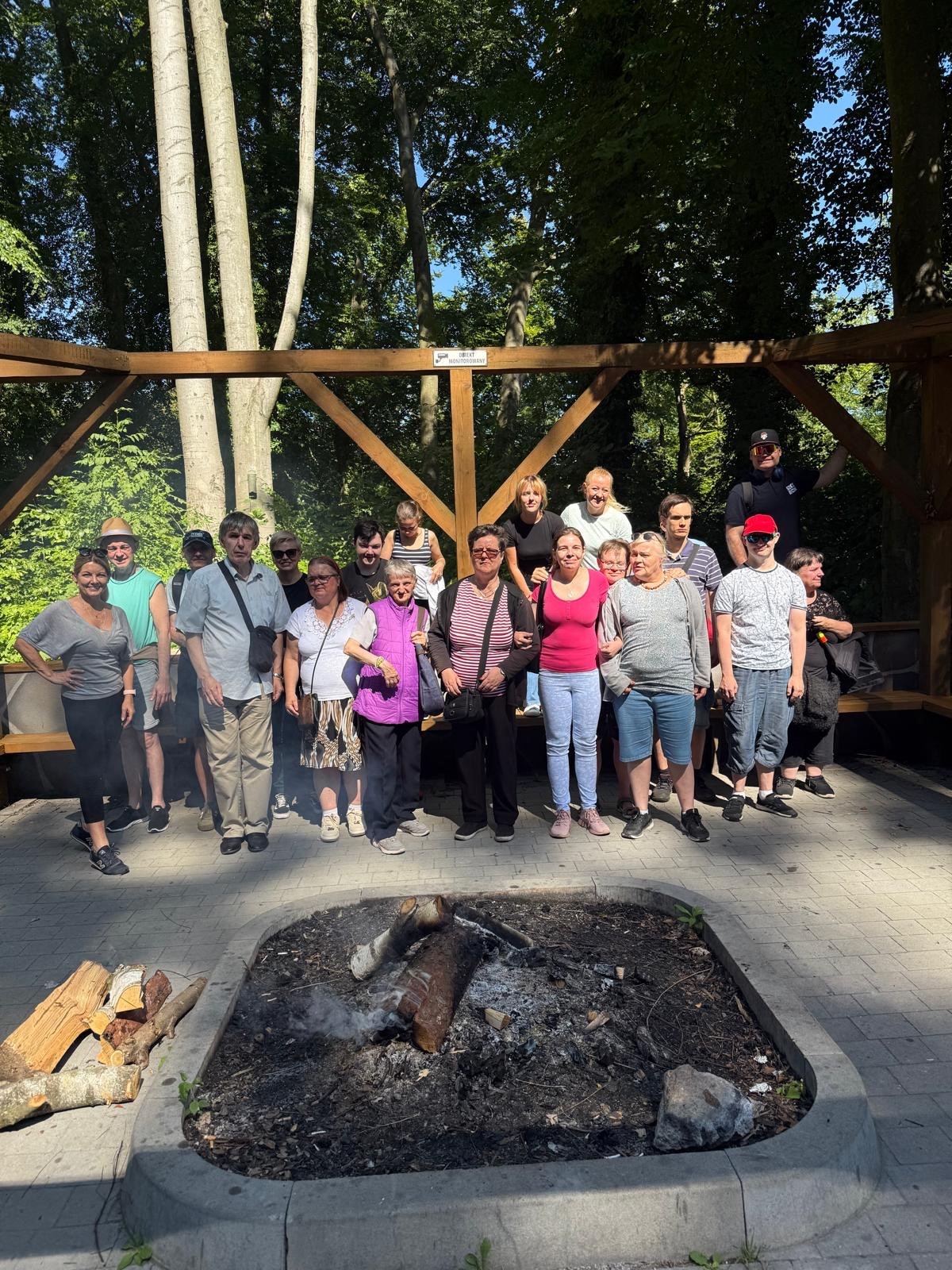 Grupa kobiet i mężczyzn pozuje do zdjęcia. Przed nimi ognisko.