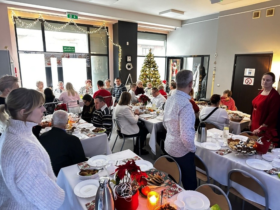 Duża grupa kobiet i mężczyzn siedzi przy stołach. 