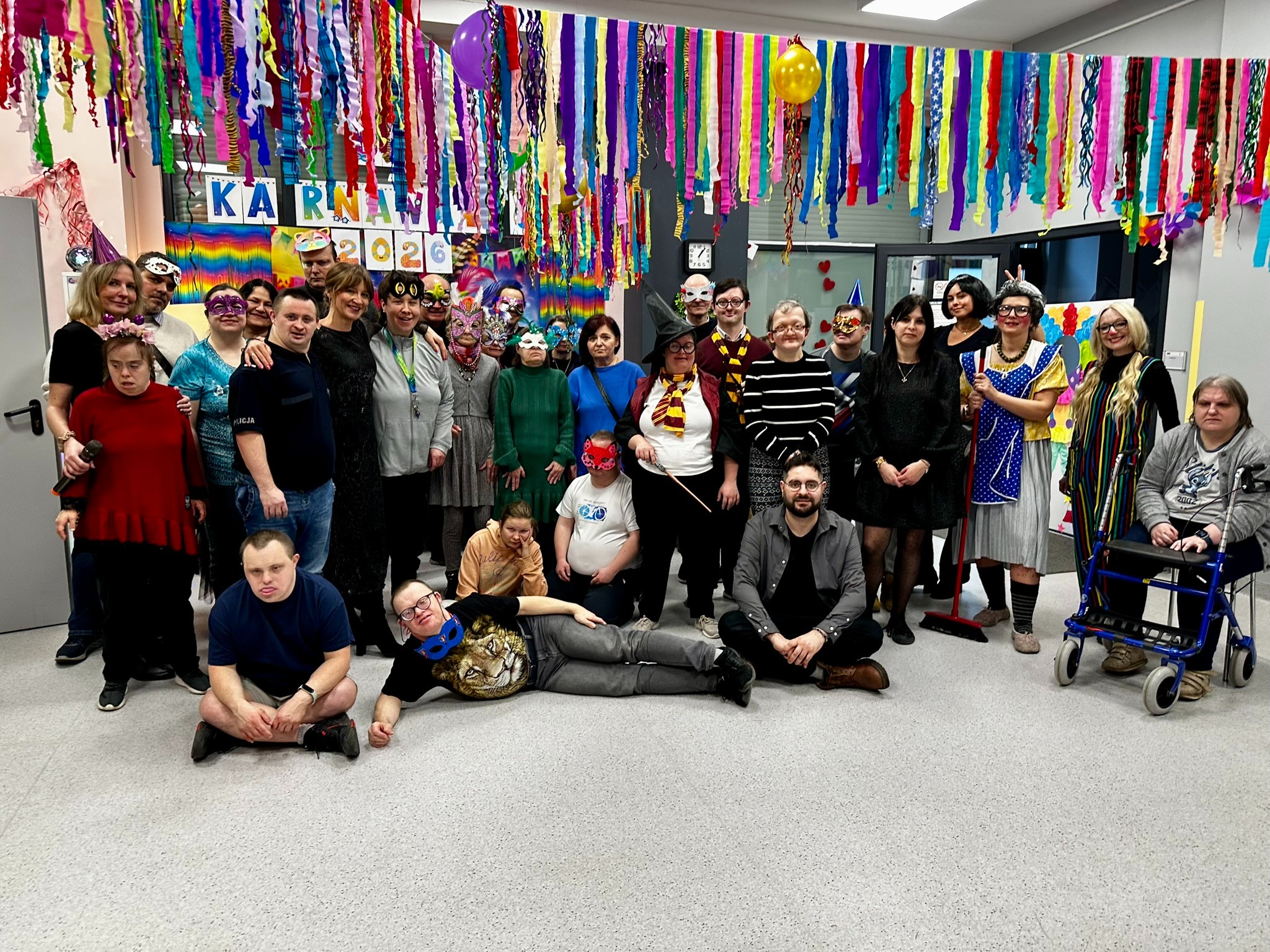 Duża grupa kobiet i mężczyzn pozuje do zdjęcia w przebraniach karnawałowych. 